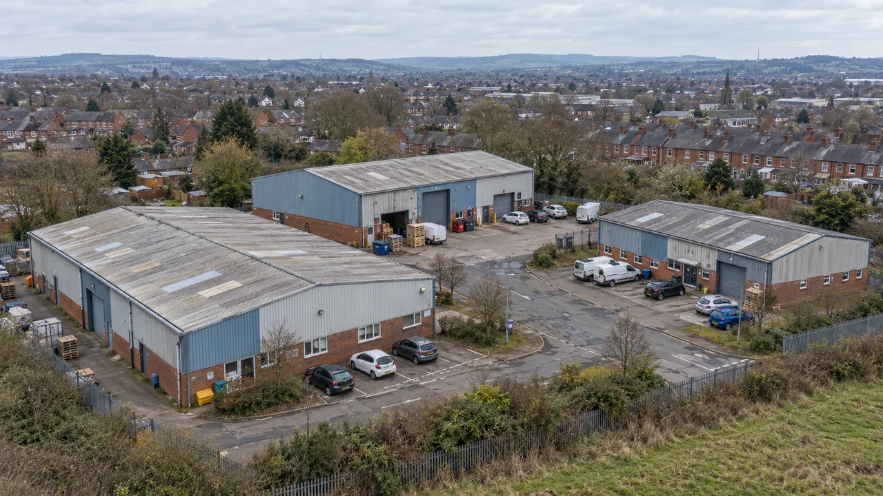 Aerial view of a working industrial estate with weathered warehouse roofs, loading areas and parked vans