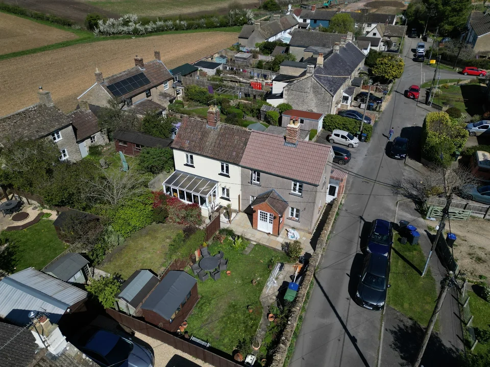 Aerial view of village homes and a road beside open fields