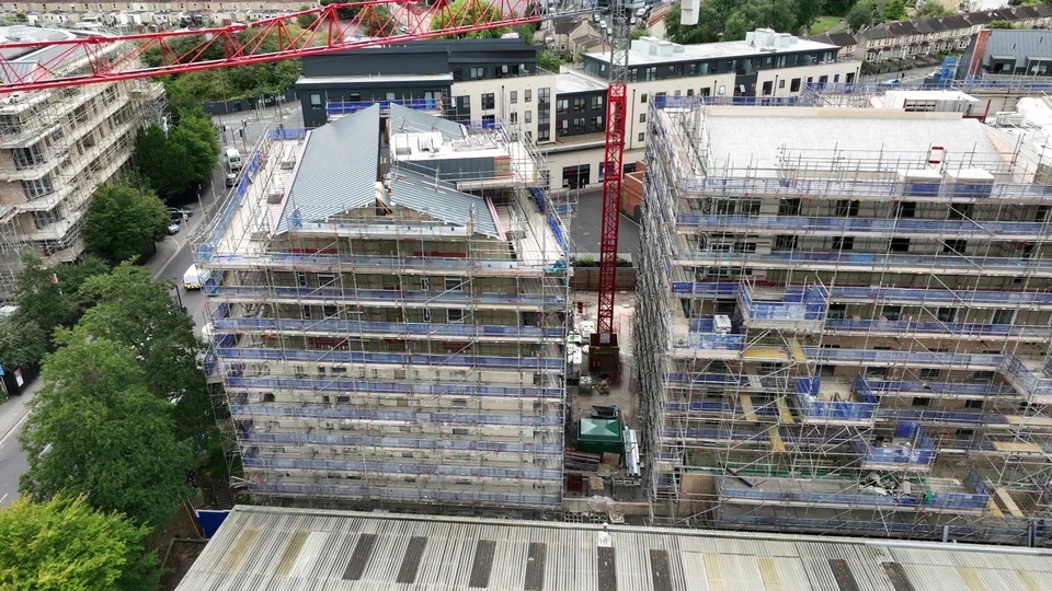 Multi storey construction buildings surrounded by scaffolding with a tower crane