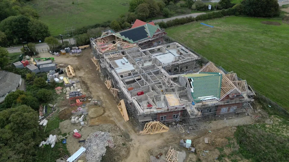Large property under construction with scaffolding, unfinished roofs and surrounding land