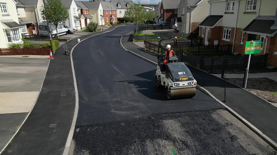 Road resurfacing works viewed along a residential street