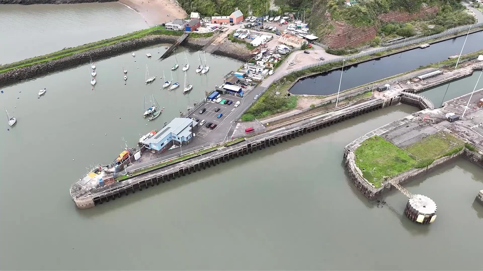 Oblique aerial view of harbour walls, waterfront buildings and boats