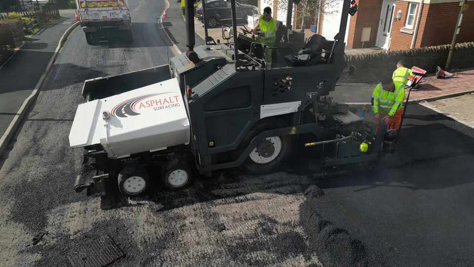 Asphalt paver and crew working on a residential road