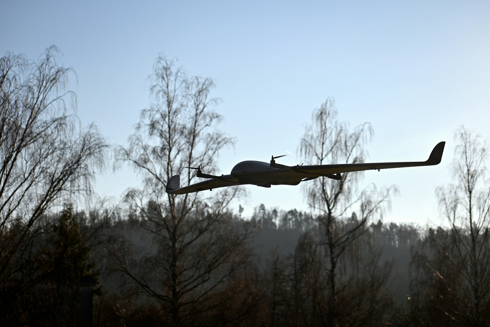 Fixed wing drone flying above trees